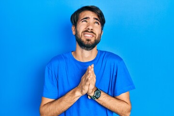 Young hispanic man wearing casual clothes begging and praying with hands together with hope...