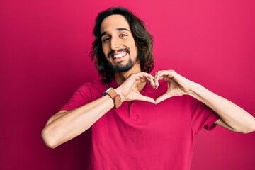 Young hispanic man wearing casual clothes smiling in love doing heart symbol shape with hands. romantic concept.