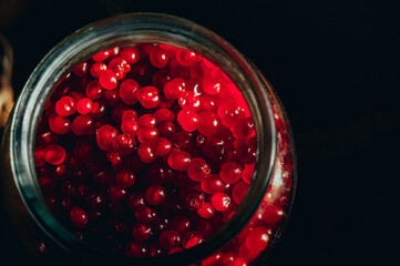 Close up harvest of berries in glass jars. Stone berry, kostyanika, rubus saxatilis. Rustic style,...
