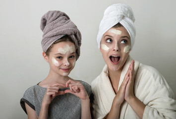 Two girls playing with cosmetic SPA mask on their faces. Little girl and young woman enjoy spa treatments. SPA and wellness