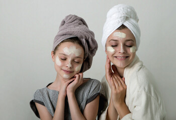 Two girls playing with cosmetic SPA mask on their faces. Little girl and young woman enjoy spa...