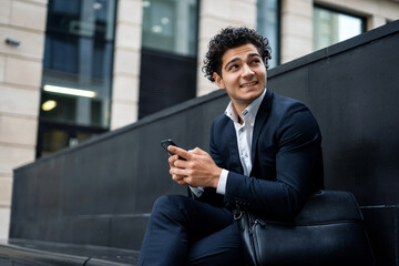 A bank employee near the office. A banker goes to work in a business suit. The lawyer responds to clients ' messages by phone. A financier makes a call to a colleague on a mobile phone.