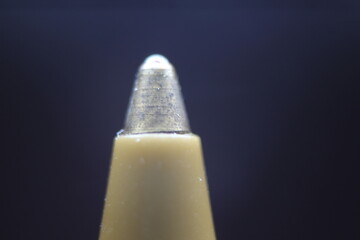 Macro photo of ballpoint pen tip with dark grey background.