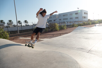 Young adult male skater riding on the skate park ramps