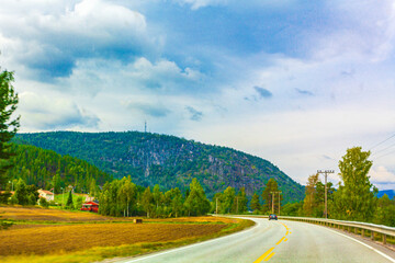 Driving through Norway in summer with mountains and fjord view.