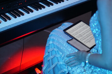 A musician girl reads sheet music on an electronic tablet before a concert