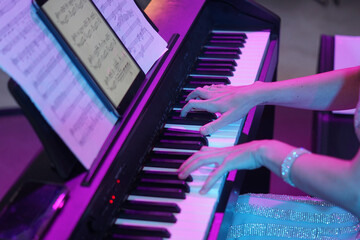the hands of a musician play the piano