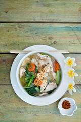 Asian soup with chicken and noodles served on green wooden background. Traditional thai food. Copyspace. Top view