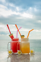 Two fresh fruit cocktails on tropical island with sea view background
