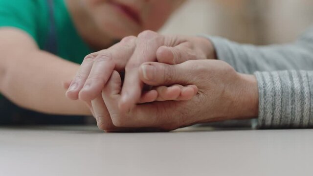 close up little boy holding grandmothers hand showing affection loving child showing compassion for granny enjoying bonding with grandson family concept 4k footage