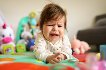 Close up on baby small caucasian girl five months old lying belly down on tummy at home in summer...