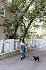 Young adult filipino woman walking dog outside on street