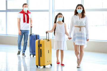 Woman and her little daughter in medical masks waiting for their flight at the airport