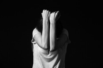 Scared young woman on dark background. Concept of harassment