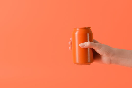 Hand with can of soda on color background
