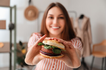 Female seller eating tasty vegan burger at workplace