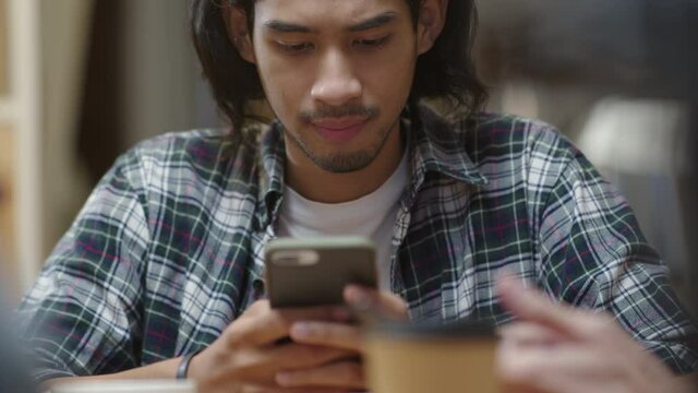 Candid bored upset asia male people sit at night pub bar cafe after work party hold phone in hand read chat watch and play on app. Social addict teen man think hard look moody sad pensive at table.