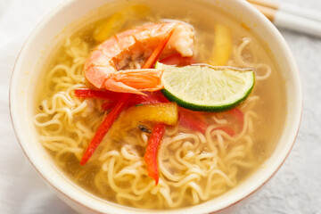 Bowl of tasty Thai soup with shrimps on table, closeup