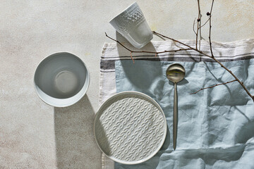 Different tableware, spoon and napkin on light background