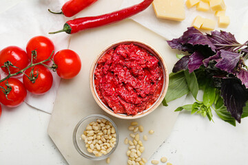 Composition with bowl of tasty pesto sauce and ingredients on light background