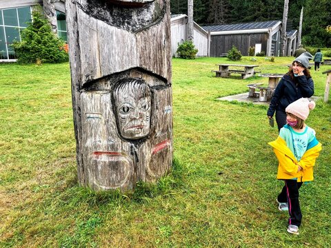 A mother and daughter admiring a totem pole at the beautiful Haida Cultural centre, in Skidegate, Haida gwaii, BC, Canada