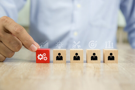 Hand choose gear icon with businessman on cube wooden block stack. Concepts of human resources op people business team creative thinking and personnel leader and teamwork or leadership team player.