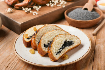 Plate with slices of tasty poppy seed bun on wooden background