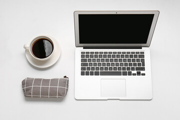 Stylish pencil case, cup of coffee and modern laptop on white background