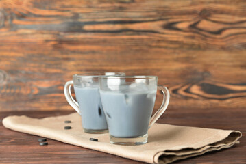 Glass cups of tasty Charcoal Latte on wooden background