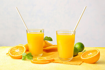 Glasses of tasty orange juice on light background