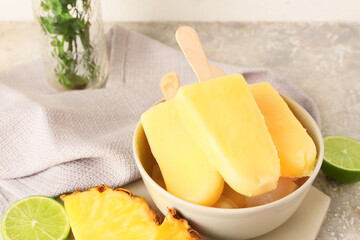 Bowl with tasty pineapple popsicles on light background