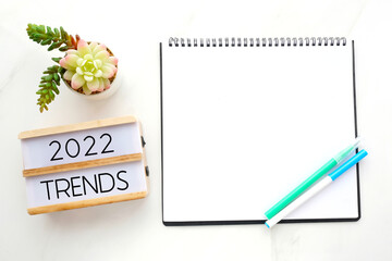 2022 trends on wooden box, Blank paper notebook and pen on white table background, new year business trend mock up, template, copy space for text