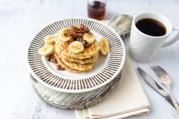 Protein pancakes topped with banana, syrup and glazed pecans. Healthy diet flapjacks. 