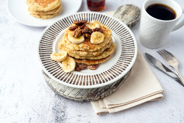 Protein pancakes topped with banana, syrup and glazed pecans. Healthy diet flapjacks. 