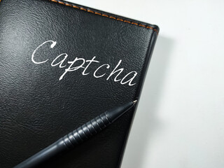 Business concept.Text Captcha writing on notebook with pen on a white background.