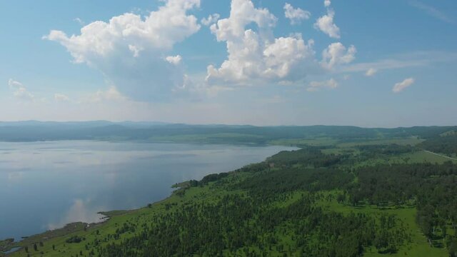 Beryozovskoye reservoir - cooling reservoir of Beryozovskaya GRES. Aerial drone view of lake landscape with road in sunny summer. Berezovskaya GRES is a thermal power plant in the town of Sharypovo