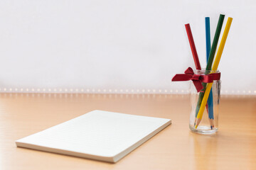 The white task pad notebook and colored pencils in glass with red ribbon.