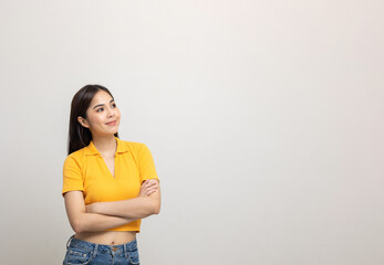Beautiful asian woman look into blank space. Smiling female wearing yellow shirt on isolated white background. Attractive Teenager girl looking at empty space for text feeling excited and surprised.