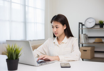 Young asian woman using laptop chatting video conference online sitting in living room at home. Business Woman looking at screen Meeting on social media live steam. Work, learning from home.