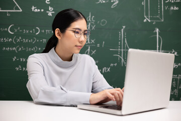 Young asian teacher woman sitting using laptop video conference with student. Female teacher training the mathematics in classroom from live stream with computer online course.