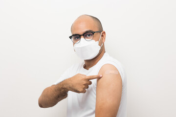 Young asian man wearing mask received a corona vaccine. Portrait of Asian man show shoulder with band aid after injection a vaccination protection the coronavirus on isolated white background.