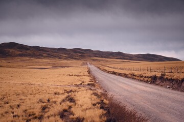 Dirt road across a vast dry grassland in Valle de Uco, Mendoza, Argentina.