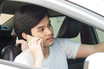 handsome teenage of Asian man uses a mobile phone in a private car.    