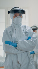 Portrait of caucasian dentist prepared for dental surgery at oral clinic, wearing protection suit with mask, face shield, gloves and coverall. Stomatology specialist looking at camera