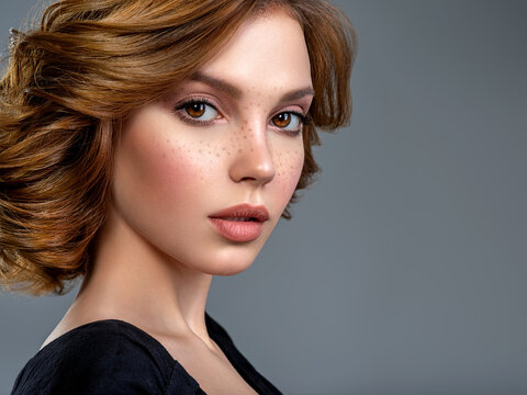 Beautiful face of an white woman. Beautiful brown haired with stylish short hairstyle. Woman with a  curly hair. Sensual young woman with freckles on face. Attractive girl with a brown makeup.
