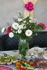 A bouquet of homemade asters in a glass vase in the decor of a country banquet