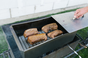 A man's hand opens a smokebox with lard in nature