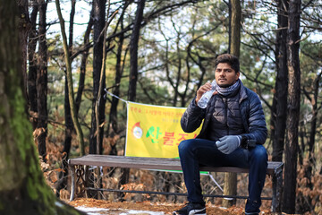 Fototapeta premium the person sitting on a bench in the park and drinking water