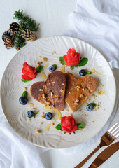 Homemade festive pastry snacks. Heart Shaped Pancake with Strawberry Flower & Blueberries. Cooked to golden brown, topped with crushed walnut, honey syrup eaten with strawberry and blueberries