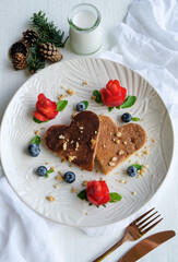 Homemade festive pastry snacks. Heart Shaped Pancake with Strawberry Flower & Blueberries. Cooked to golden brown, topped with crushed walnut, honey syrup eaten with strawberry and blueberries